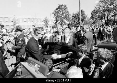 Kongreßfeldzug Reise: Cleveland, Ohio, Ankunft, Rallye, Autokolonne, Abfahrt. Präsident John F. Kennedyu2019s hält während einer Wahlkampfreise vor der St. Edward High School in Lakewood, Ohio; Präsident Kennedy schüttelt die Hände mit Bruder Florentius Schu als Rektor, Bruder Charles Krupp, schaut auf. Ebenfalls abgebildet: Repräsentant Michael J. Feighan aus Ohio (im Vordersitz des Cabrios, Rücken zur Kamera); Senator Frank Lausche aus Ohio (auf dem Rücksitz mit Präsident Kennedy); Gouverneur von Ohio, Michael V. DiSalle (ganz rechts im Vordergrund); Vorsitzender des Cu Stockfoto