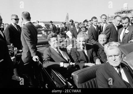 Kongreßfeldzug Reise: Cleveland, Ohio, Ankunft, Rallye, Autokolonne, Abfahrt. Präsident John F. Kennedy sitzt in einem Cabrio mit Ohio Beamten bei der Ankunft am Cleveland Hopkins Airport in Cleveland, Ohio, während einer Kongresskampagne Reise. Senator Frank Lausche und Gouverneur Michael V. DiSalle sitzen auf dem Rücksitz mit Präsident Kennedy; Vertreter Michael J. Feighan sitzt auf dem Vordersitz. White House Secret Service Agent, Bill Duncan, steht hinter dem Auto auf der rechten Seite. Stockfoto