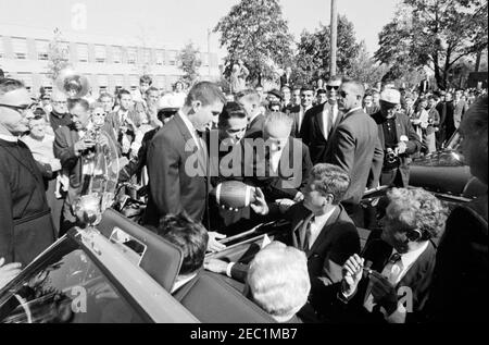 Kongreßfeldzug Reise: Cleveland, Ohio, Ankunft, Rallye, Autokolonne, Abfahrt. Präsident John F. Kennedyu2019s Autokolonne hält vor der St. Edward High School in Lakewood, Ohio, während einer Kongresskampagne Reise; Präsident Kennedy erhält einen Fußball im Namen der Studentenschaft von Senior Class Präsident Robert Cutter, und Rektor, Bruder Charles Krupp. Ebenfalls abgebildet: Repräsentant Michael J. Feighan aus Ohio (im Vordersitz des Cabrios, Rücken zur Kamera); Senator Frank Lausche aus Ohio (auf dem Rücksitz mit Präsident Kennedy); Gouverneur von Ohio, Michael V. DiSalle (stehend bei f Stockfoto