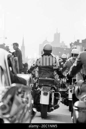 Wahlkampfreise im Kongress: Buffalo, New York, Kundgebung. Präsident John F. Kennedy winkt aus einem Cabrio, während seine Autokolonne während einer Wahlkampfreise durch Buffalo, New York, fährt. Motorradbegleiter reisen neben dem President Kennedyu2019s Auto. Stockfoto