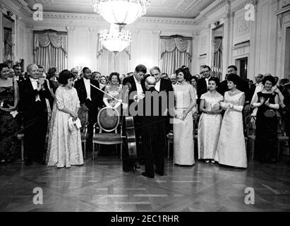 Abendessen zu Ehren des Gouverneurs Luis Muu00f1oz Maru00edn von Puerto Rico, 8:00pm Uhr. Präsident John F. Kennedy und Gouverneur von Puerto Rico Luis Muu00f1oz Maru00edn sprechen mit dem Cellisten Pablo Casals nach seinem Auftritt bei einem Staatsessen zu Ehren des Gouverneurs Muu00f1oz Maru00edn. Erste Reihe (L-R): Mary Louise Day; Postmaster General J. Edward Day; Inu00e9s Mendoza de Muu00f1oz; Präsident Kennedy; Mr. Casals; Gouverneur Muu00f1oz Maru00edn; First Lady Jacqueline Kennedy; Marta Casals; Rose Kennedy; und Dorothy Goldberg, Ehefrau des Arbeitsministers Arthur Goldberg. East Room, White House, Washington, Stockfoto