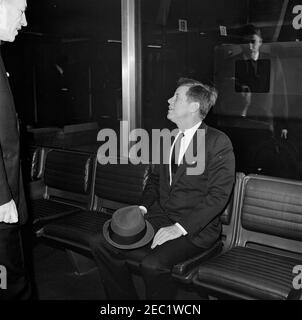 Dedication Ceremonies, Dulles International Airport, 11:12am Uhr. Präsident John F. Kennedy (Holding hat) sitzt in einer der mobilen Lounges am Dulles International Airport während der Einweihungszeremonie für den Flughafen nach dem verstorbenen Staatssekretär John Foster Dulles benannt. Der Verwalter des Luftfahrtbundesamtes (FAA), Najeeb Halaby (teilweise versteckt am Rand des Rahmens), steht links. Chantilly, Virginia. Stockfoto