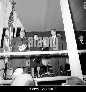 Dedication Ceremonies, Dulles International Airport, 11:12am Uhr. Präsident John F. Kennedy nimmt an der Einweihungszeremonie für den internationalen Flughafen Dulles Teil, benannt nach dem verstorbenen Außenminister John Foster Dulles. Von links nach rechts: Kaplan des Senats der Vereinigten Staaten, Reverend Frederick Brown Harris; Janet Avery Dulles (Witwe des ehemaligen Sekretärs Dulles); Chef der Marineoperationen, Admiral George W. Anderson, Jr. (hinten); Präsident Kennedy; Oberrichter des Obersten Gerichtshofs, Earl Warren (meist hinter dem Präsidenten versteckt); Verwalter des Luftfahrtbundesamtes (FAA), Najeeb Halaby. Ch Stockfoto