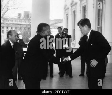 Mittagessen zu Ehren von Sylvanus Olympio, Präsident von Togo, 1:00pm Uhr. Präsident John F. Kennedy (rechts) schüttelt die Hände mit Präsident von Togo, Sylvanus Olympio, bei der Ankunft von Präsident Olympiou2019s im Weißen Haus für ein Mittagessen zu seinen Ehren. Chef des Protokolls, Angier Biddle Duke, steht ganz links; Fotografen, darunter Wochenschau-Fotograf für United Press Movietone, Thomas J. Craven, Sr., stehen im Hintergrund. North Portico, White House, Washington, D.C. Stockfoto