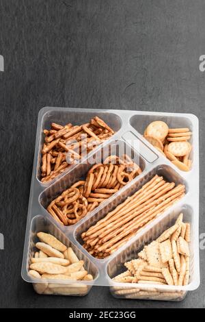 Knusprige Mischung aus Brezeln und Crackern mit Sesam und Mohn Samen auf schwarzem Stein Hintergrund Stockfoto