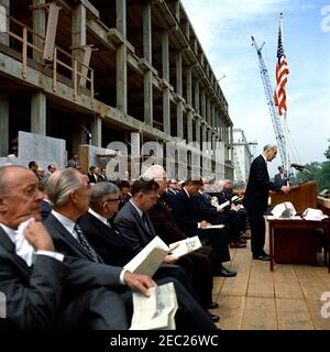 Grundsteinlegung, Bürogebäude Rayburn House, 10:28am Uhr. Der Sprecher des Repräsentantenhauses und Vorsitzender der House Office Building Commission, John W. McCormack aus Massachusetts (am Rednerpult), hält bei der Grundsteinlegung für das Rayburn House Office Building, das dem verstorbenen Sprecher des Hauses, Sam Rayburn, gewidmet ist, Bemerkungen; Präsident John F. Kennedy sitzt im Zentrum. Ebenfalls im Bild: Repräsentantin Leslie C. Arends (Illinois); Repräsentantin Clarence Cannon (Missouri); Repräsentant Carl Albert (Oklahoma); Oberrichter des Obersten Gerichtshofs, Earl Warren; Mitglied Stockfoto