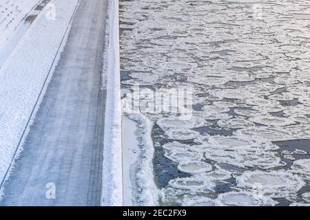 Viele gebrochene Eisstücke, die im Winter durch den Fluss, den gefrorenen Fluss und das Eisufer treiben Stockfoto