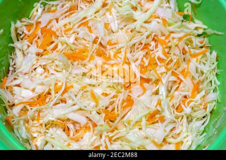 Weißkohl in Scheiben geschnitten und mit Karotten in einer Schüssel gemischt Zum Beizen Stockfoto