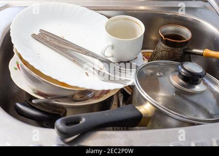 Schmutziges Geschirr nach dem Abendessen liegen im Waschbecken und reinigen den Tisch in der Küche Stockfoto