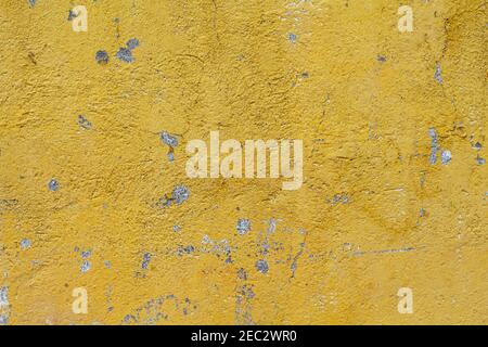 Verwitterte gelb lackierte Betonwand. Sonnige raue Gips Foto Textur. Schäbig schicke Kulisse. Alte Betonoberfläche mit Flecken. Verquerte Textur Stockfoto