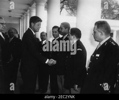 Besuch der Mitglieder des Interamerikanischen Verteidigungsausschusses im Rosengarten, 12:06pm Uhr. Präsident John F. Kennedy besucht mit Delegierten des Interamerikanischen Verteidigungsausschusses (anlässlich des boardu2019s 20th-jährigen Bestehens) in der Westflügel-Kolonnade des Weißen Hauses, Washington, D.C., von links nach rechts: Nicht identifizierter Dolmetscher (am Rand des Rahmens); nicht identifizierter Mann (im Rücken); Präsident Kennedy; Oberst Fidel Su00e1nchez Hernu00e1ndez, Armee Salvadorians; zwei nicht identifizierte Männer; Major Cecilio Castro, honduranische Armee (Hände schüttelnd mit dem Präsidenten); nicht identifiziert. Stockfoto