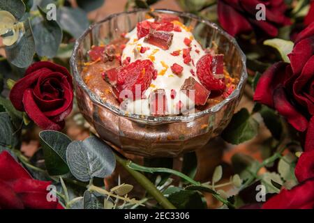 Eine köstliche Schokolade Mousse mit Creme Fraiche Cremes und gekrönt Schokoladenstückchen umgeben von romantischen Valentinen-Rosen Stockfoto