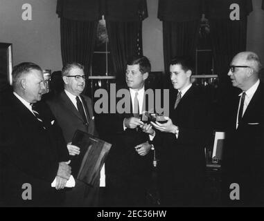 Besuch des Boysu0027 Clubsu0027 u0022Boy des Jahres,u0022 Stephen Lutz, 10:57AM. Präsident John F. Kennedy (Mitte) hält ein Modell im Maßstab, eingeschlossen in einer Flasche, von PT Boot 109, präsentiert ihm von den Boysu0027 Clubs von Americau0027s (BCA) u0022Boy der Yearu0022 Stephen Lutz von Newark, New Jersey. (L-R) Albert L. Cole, Präsident der BCA; John M. Gleason, Nationaldirektor der BCA; Präsident Kennedy; Stephen Lutz; und Charles R. Messier, Executive Director der Boysu0027 Clubs von Newark, New Jersey. Oval Office, White House, Washington, D.C. Stockfoto