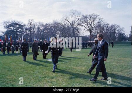 Ankunftszeremonie für Abdirashid Ali Shermarke, Premierminister der somalischen Republik, 11:45am Uhr. Präsident John F. Kennedy geht mit dem Premierminister der somalischen Republik, Dr. Abdirashid Ali Shermarke, während der Ankunftszeremonien zu Ehren von Premierminister Shermarke; ein nicht identifizierter Kommandant der Truppen geht links von Präsident Kennedy und dem Premierminister. Militärische Farbe und Ehre Garde Truppen stehen auf die Aufmerksamkeit im Hintergrund. South Lawn, White House, Washington, D.C. [Makel auf dem Bild sind original auf das Negative.] Stockfoto