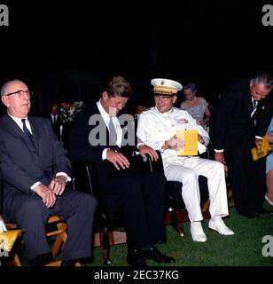 Präsident Kennedy blickt auf die Marine Corpsu0027 Evening Parade, in den Marine Barracks Washington, D.C. (8th u0026 I Streets, SE), 9:00pm Uhr. Präsident John F. Kennedy lacht mit dem Kommandanten des United States Marine Corps, General David M. Shoup, in den Marine Barracks (u201c8th u0026 Iu201d) in Washington, D.C.; Präsident Kennedy nahm an einer Abendparade in der Baracke Teil. Senator Richard B. Russell (Georgia) sitzt ganz links, Vizepräsident Lyndon B. Johnson sitzt ganz rechts. Stockfoto