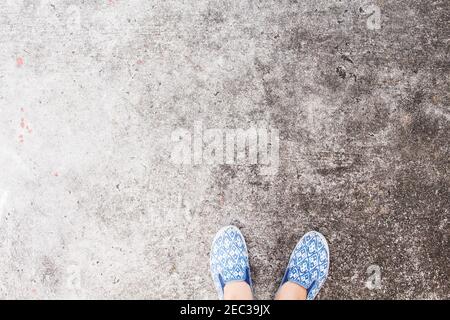 Frauenfüße in Wanderschuhen auf Asphaltstraße. Industrielle Beton Boden Draufsicht Foto. Urban Walk Banner. Veraltete Hintergrundtextur. Grungy backdr Stockfoto