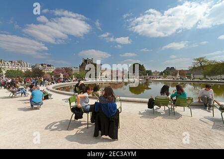 Jardin de Tuileries, Paris. Touristen und Pariser entspannen sich in der Frühlingssonne an einem der Springbrunnen-Pools in den formellen Gärten. Stockfoto