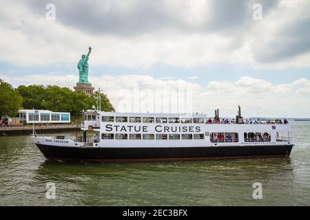 Statue Cruises Fähre, die Touristen zur Freiheitsstatue bringt Mit der Statue im Hintergrund Stockfoto