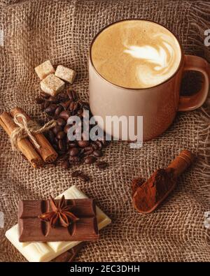 tasse Kaffee mit Zimt, Anis, Kaffeebohne, Schokolade und Zucker auf Holzgrund Stockfoto