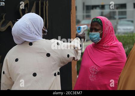 Ein Moscheebeamter nimmt die Körpertemperatur eines Verehrers mit einem Thermometer am Eingang zur zentralen Moschee von Lagos. Aufgrund der Coronavirus-Pandemie in Nigeria fordern viele religiöse Kultstätten wie die zentrale Moschee von Lagos ihre Mitglieder auf, die Präventivprotokolle von Covid-19 einzuhalten. Lagos, Nigeria. Stockfoto