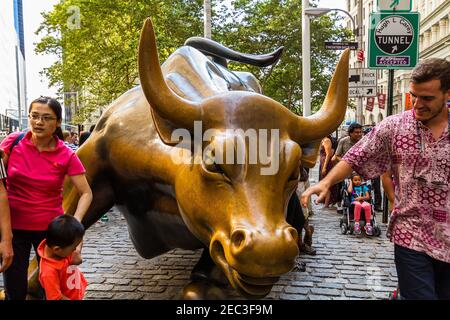 Eine Bullen-Statue, auch bekannt als Wall Street Bull, im Finanzviertel von Manhattan, New York, mit Touristen um sie herum Stockfoto