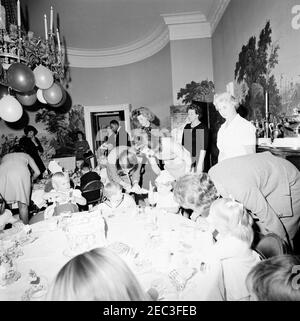 Geburtstagsfeier für Caroline Kennedy und John F. Kennedy, Jr.. John F. Kennedy, Jr. (Mitte rechts), sitzt an einem Tisch im Presidentu2019s Dining Room (Residenz) des Weißen Hauses, Washington, D.C., während einer gemeinsamen Geburtstagsfeier für ihn und seine Schwester Caroline Kennedy; First Lady Jacqueline Kennedy steht hinter ihrem Sohn. Ebenfalls im Bild: Eunice Kennedy Shriver; erste Sozialministerin von Ladyu0027s, Letitia Baldrige; Butler des Weißen Hauses, Johnny Johnson. Stockfoto