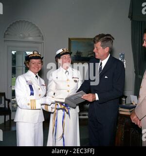 Besuch von Kapitän Winifred Quick Collins, Direktor der Frauen für Volunteer Emergency Service (WAVES), 9:48am. Präsident John F. Kennedy erhält ein Geschenk eines Buches von US Navy Offizieren. Von links nach rechts: Frauen für Volunteer Emergency Service (WAVES) Offizier, Commander Irene Wolensky; Direktor von WAVES, Kapitän Winifred Quick Collins; Präsident Kennedy; und Naval Aide an den Präsidenten, Kapitän Tazewell T. Shepard, Jr. Oval Office, White House, Washington, D.C. Stockfoto