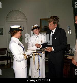 Besuch von Kapitän Winifred Quick Collins, Direktor der Frauen für Volunteer Emergency Service (WAVES), 9:48am. Präsident John F. Kennedy erhält ein Geschenk eines Buches von US Navy Offizieren. Von links nach rechts: Frauen, die für den Volunteer Emergency Service (WAVES) Officer, Commander Irene Wolensky, Direktorin von WAVES, Captain Winifred Quick Collins und Präsident Kennedy akzeptiert wurden. Oval Office, White House, Washington, D.C. Stockfoto