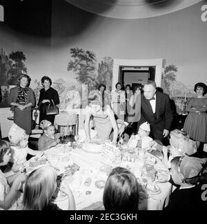 Geburtstagsfeier für Caroline Kennedy und John F. Kennedy, Jr.. First Lady Jacqueline Kennedy legt Caroline Kennedyu0027s Kuchen auf den Tisch während einer gemeinsamen Geburtstagsfeier für Caroline und John F. Kennedy, Jr. Avery Hatcher, Sohn des Associate Press Secretary, Andrew T. Hatcher, sitzt links von Caroline; Butler des Weißen Hauses, John W. Ficklin, steht rechts. Presidentu2019s Esszimmer (Residenz), White House, Washington, D.C. Stockfoto