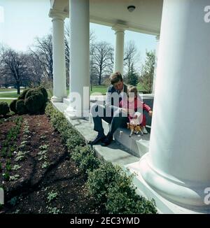 Präsident Kennedy mit John F. Kennedy, Jr. (JFK, Jr.), u0026 Caroline Kennedy (CBK). Präsident John F. Kennedy und sein Sohn John F. Kennedy jr. Spielen mit einem Spielzeugpferd in der West Wing Colonnade des Weißen Hauses, Washington, D.C. Stockfoto