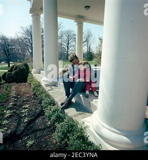Präsident Kennedy mit John F. Kennedy, Jr. (JFK, Jr.), u0026 Caroline Kennedy (CBK). Präsident John F. Kennedy und sein Sohn John F. Kennedy jr. Spielen mit einem Spielzeugpferd in der West Wing Colonnade des Weißen Hauses, Washington, D.C. Stockfoto