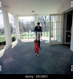 Präsident Kennedy mit John F. Kennedy, Jr. (JFK, Jr.), u0026 Caroline Kennedy (CBK). Präsident John F. Kennedy und sein Sohn John F. Kennedy jr. Spielen mit einem Spielzeugpferd in der Westflügel-Kolonnade des Weißen Hauses, Washington, D.C., EINE Tür zum Oval Office ist rechts offen. Stockfoto