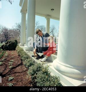 Präsident Kennedy mit John F. Kennedy, Jr. (JFK, Jr.), u0026 Caroline Kennedy (CBK). Präsident John F. Kennedy und sein Sohn John F. Kennedy jr. Spielen mit einem Spielzeugpferd in der West Wing Colonnade des Weißen Hauses, Washington, D.C. Stockfoto