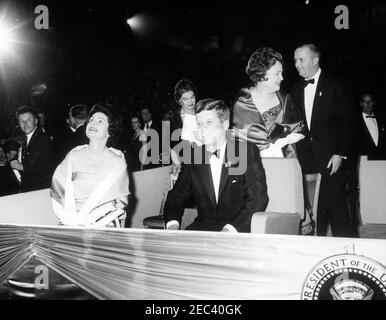 Zweiter Eröffnungsgruß zum Präsidenten-Abendessen, 7:30pm Uhr. Präsident John F. Kennedy (rechts) und Lady Bird Johnson (links, Blick nach oben) sitzen in der Presidential Box während der zweiten Antrittsgruß an den Präsidenten, der an den zweiten Jahrestag der Amtseinführung von Präsident Kennedyu0027s erinnert. Bedford S. Wynne, Vorsitzender der Veranstaltung (zwei Personen hinter Präsident Kennedy), steht im Hintergrund; alle anderen sind nicht identifiziert. National Guard Armory, Washington, D.C. Stockfoto