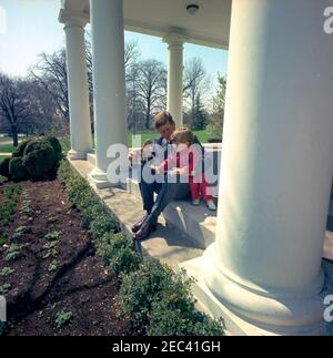 Präsident Kennedy mit John F. Kennedy, Jr. (JFK, Jr.), u0026 Caroline Kennedy (CBK). Präsident John F. Kennedy und sein Sohn John F. Kennedy jr. Spielen mit einem Spielzeugpferd in der West Wing Colonnade des Weißen Hauses, Washington, D.C. Stockfoto