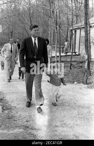 Wochenende im Camp David. Präsident John F. Kennedy und John F. Kennedy, Jr. (halten seine fatheru0027s Hand), gehen entlang eines Pfades in Camp David in Frederick County, Maryland. Dahinter folgen Kennedy-Familienhund, u0022Charlieu0022 (ganz links); Kennedy-Familienfreund und Untersekretär der Marine, Paul u0022Redu0022 Fay mit seiner Tochter Sally Fay (teilweise versteckt); White House-Filmfotograf, Leutnant Thomas M. Atkins (hinten); und First Lady Jacqueline Kennedy (teilweise versteckt). Stockfoto