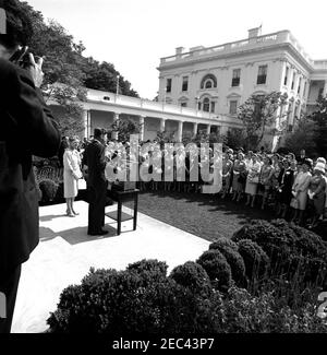 Besuch des Nationalrates der Liga der Frauen Wähler, 9:55am. Präsident John F. Kennedy spricht im Rosengarten des Weißen Hauses, Washington, D.C., an eine Gruppe von Vertretern des Nationalrats der Liga der Wählerinnen (LWV).Neben Präsident Kennedy steht Präsidentin des LWV, Ruth S. Phillips; alle anderen sind nicht identifiziert. Stockfoto