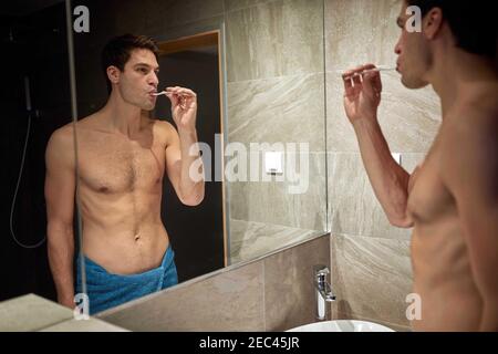 Mann, der morgens im Badezimmer die Zähne putzt Stockfoto