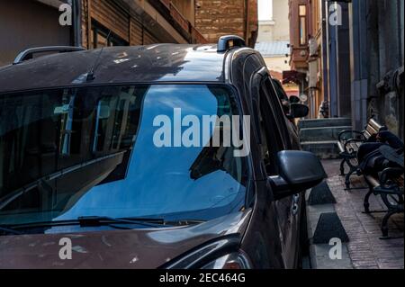 Modernes Auto in einer engen Straße in Istanbul, Türkei. Der Kontrast zwischen dem großen Himmel im Autoglas und der engen Straße. Selektiver Fokus Stockfoto