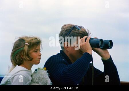 Wochenende im Hafen von Hyannis: Präsident Kennedy, Caroline Kennedy (CBK) auf der Yacht. Präsident John F. Kennedy (schaut durch ein Fernglas) sitzt neben seiner Tochter Caroline Kennedy an Bord der Präsidentenyacht u201cHoney Fitz,u201d vor der Küste von Hyannis Port, Massachusetts. [Grüner Streifen in Carolineu0027s Haaren ist original auf das Negative.] Stockfoto