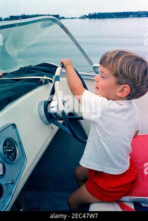 Labor Day Wochenende im Hyannis Hafen: John F. Kennedy, Jr. (JFK Jr.), am Steuer des Schnellbootes. John F. Kennedy, Jr., sitzt am Steuer eines Schnellbootes während des Labor Day Wochenendes in Hyannis Port, Massachusetts. Stockfoto