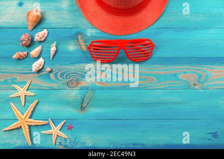 Reise- und Urlaubshintergrund mit lebenden korallenfarbenen Hut, Muscheln und Seesternen auf blau bemalten Vintage Holztisch. Flach liegend, Draufsicht mit Stockfoto