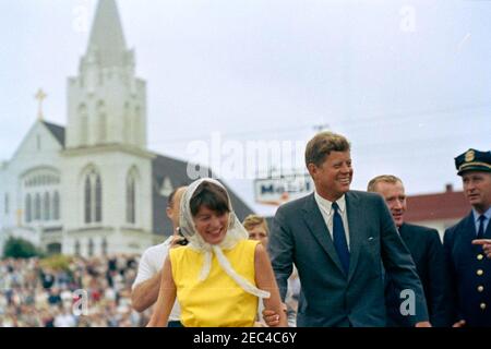 Wochenendfahrt in Maine: Messe in der Our Lady Queen of Peace Church, Boothbay Harbor; Blick auf Boothbay Harbor; an Bord von Guardian II (PT 809) und Horsewhip II. Präsident John F. Kennedy (rechts) und seine Schwester Patricia u201cPatu201d Kennedy Lawford (links) gehen zum Pier in Boothbay Harbor, Maine, nach der Messe in der Our Lady Queen of Peace Kirche (im Hintergrund sichtbar). Unter Sekretär der Marine, Paul B. u201cRedu201d Fay, geht hinter (rechts von Präsident Kennedy). Stockfoto