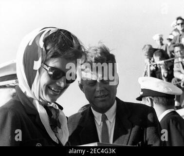 Präsident Kennedy beobachtet das 1st Americau0027s Cup Race. Präsident John F. Kennedy und First Lady Jacqueline Kennedy sehen ein Schiffsmodell des Zerstörers, USS Joseph P. Kennedy, Jr., gegeben als Geschenk von der Mannschaft des Joseph P. Kennedy, Jr., während sie das erste Rennen des 1962 Americau0027s Cup an Bord des Zerstörers teilnahmen. Naval Aide to the President, Captain Tazewell Shepard, steht auf der rechten Seite (Gesicht verdeckt). Newport, Rhode Island. Stockfoto