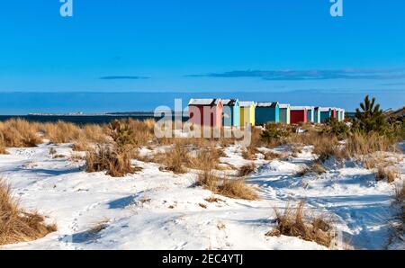 FINDHORN BAY MORAY FIRTH SCOTLAND BUNTE HÜTTEN ODER CHALETS EIN SCHNEEBEDECKTER STRAND Stockfoto