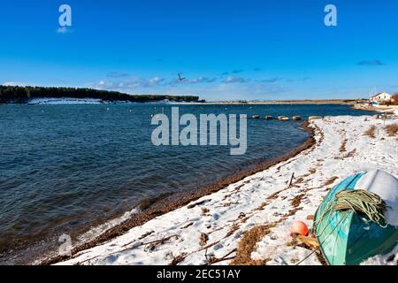 FINDHORN BAY MORAY FIRTH SCHOTTLAND WINTER SCHNEEBEDECKTER KIESSTRAND BEI FLUT GRÜNES FISCHERBOOT LIEGT IM SCHNEE Stockfoto