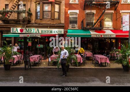 Kellner putzen Tische im italienischen Restaurant 'La Mela' ein Little Italy und ein anderer Kellner lächeln und posieren für die Kamera mit dem Daumen nach oben Stockfoto