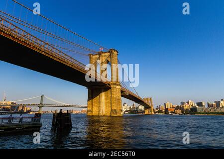 Blick auf die Brooklyn Bridge vom East River aus Greenway in Manhattan mit Menschen, die unter der Brücke stehen Eine Aussichtsplattform Stockfoto
