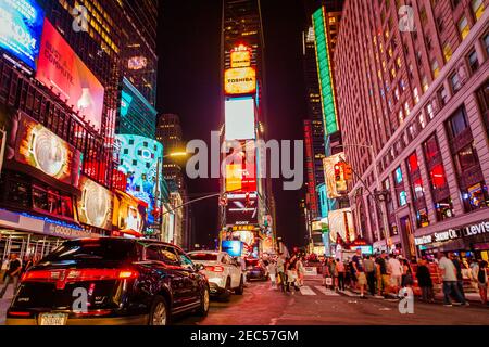 Verschwommene Autos und Leute, die nachts am Times Square herumlaufen Stockfoto