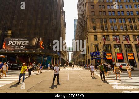 7th Avenue Street in Manhattan, New York City mit Leuten, die die Straße überqueren und mit einer Werbetafel Stockfoto